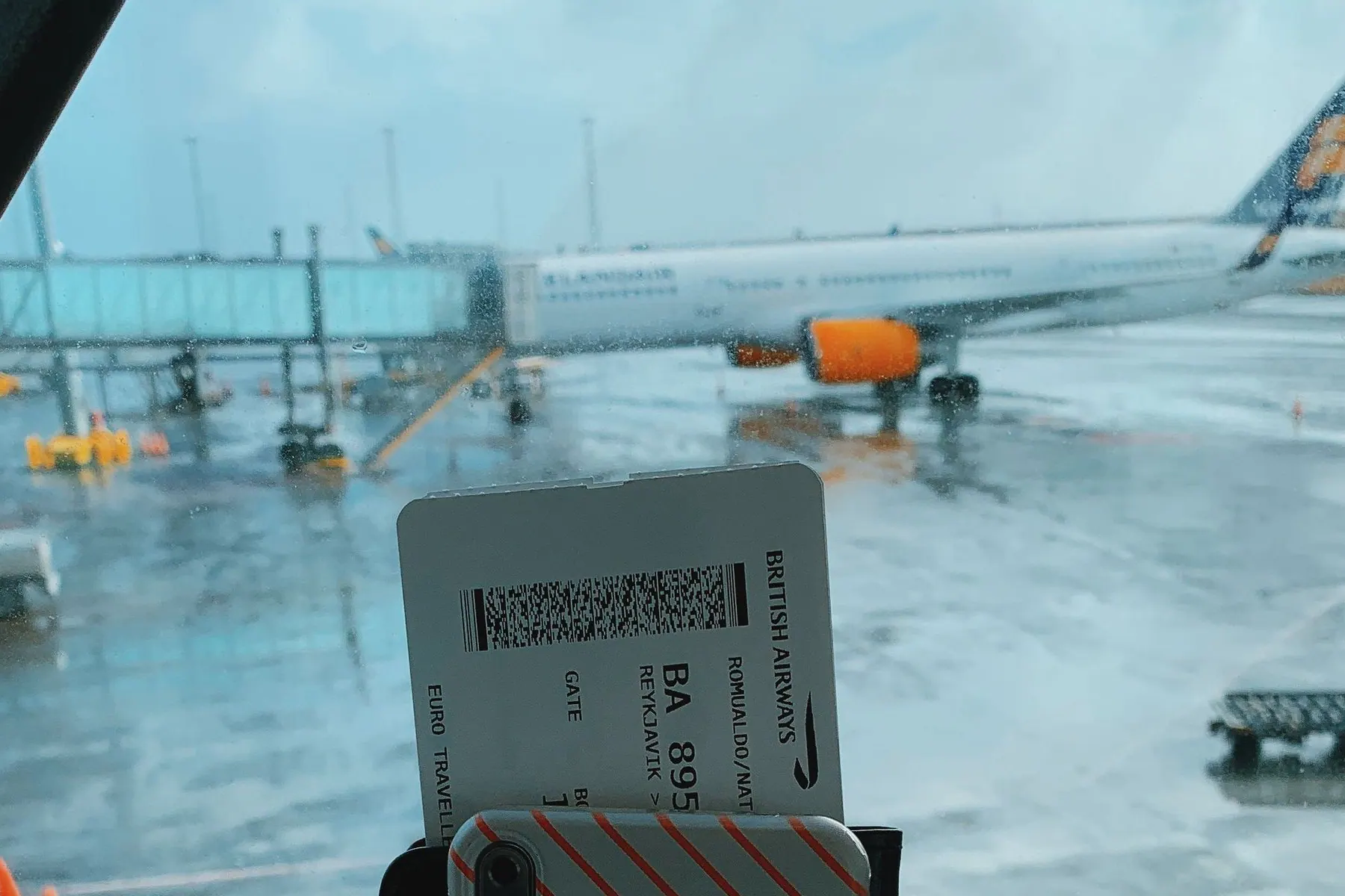 Boarding pass held against an airport apron and onward aircraft